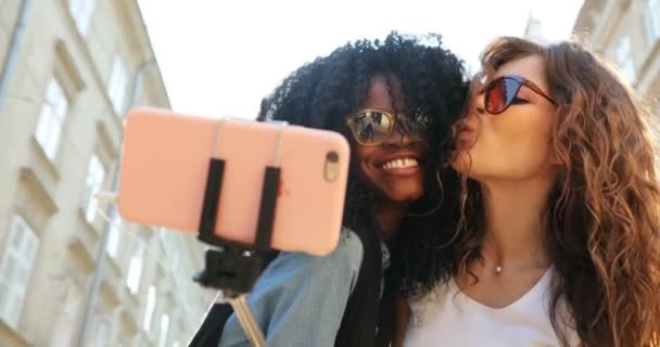 Wesoły wielokulturowym dziewczyny są robienia selfie. Są uśmiechnięte i wysyłanie pocałunki powietrza. Miejsca na świeżym powietrzu. — Wideo stockowe
