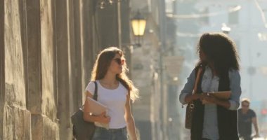 İki mutlu çok kültürlü öğrenci kayıt tutarak yürüyüşü. Yakın çekim görünümü.