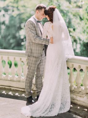 Neşeli yeni evliler sarılma ve balkonda kafa kafaya ayakta.