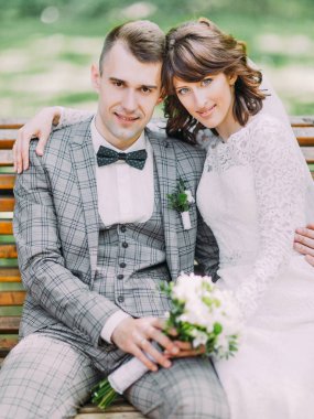 Yakın çekim sarılma ve bankta oturan yeni evliler portresi.