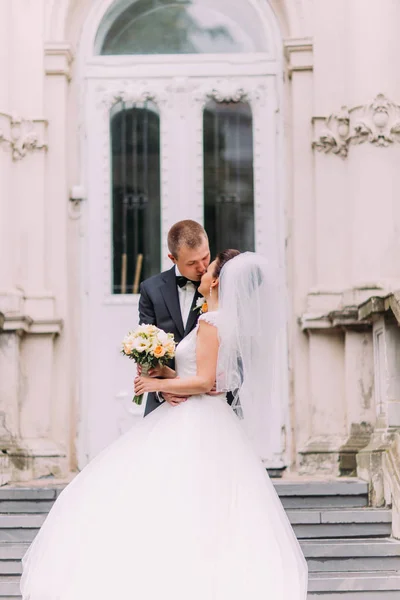 El retrato vertical de la pareja recién casada besándose en el fondo del viejo edificio austriaco . — Foto de Stock