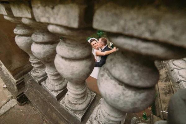 A vista de velhas barreiras góticas do noivo beijando a noiva na bochecha . — Fotografia de Stock