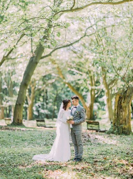 O retrato completo dos recém-casados de mãos dadas no parque ensolarado . — Fotografia de Stock