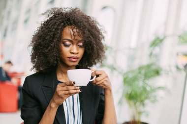 Kafede çay fincan tutan büyüleyici Afro-Amerikan hassas yakın çekim portre.