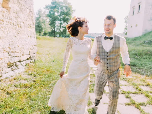 Gli sposi sorridenti si tengono per mano durante la loro passeggiata in campagna. Il ritratto ravvicinato . — Foto Stock