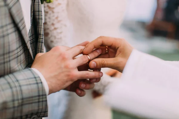 Крупным планом священник надевает обручальное кольцо на палец жениха . — стоковое фото