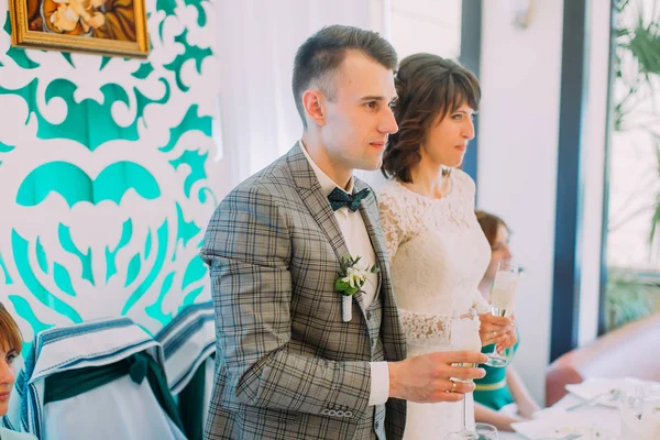 El retrato lateral de cerca de los recién casados felices sosteniendo las copas con champán . —  Fotos de Stock