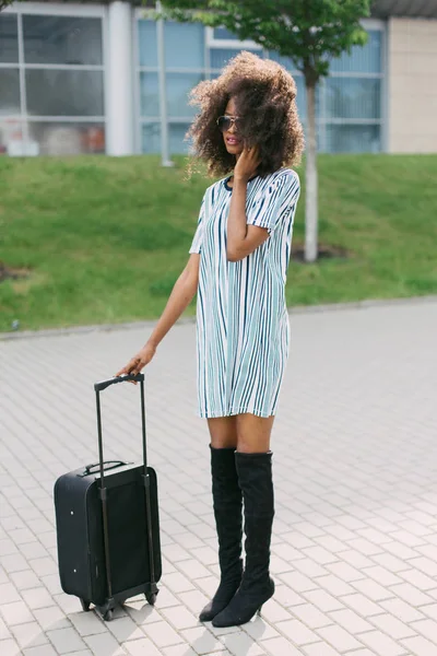 Güzel Afro-Amerikan kız Bagaj ile ayakta ve sokakta cep telefonu üzerinden konuşmak.