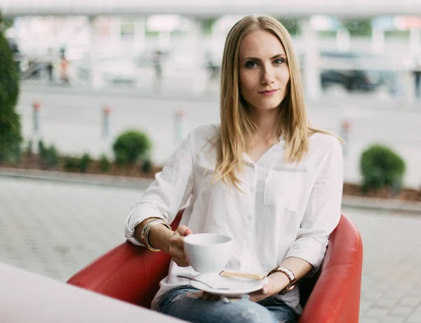 Hermosa mujer joven sosteniendo la taza de té en el café . — Foto de Stock