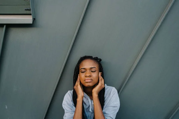 Retrato de cerca de la chica afroamericana seria con los ojos cerrados escuchando música en los auriculares . —  Fotos de Stock