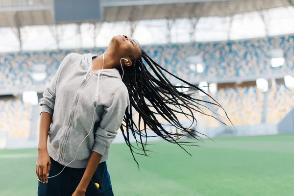 O cabelo do adolescente afro-americano no fundo turvo do estádio. Ela está a abanar a cabeça . — Fotografia de Stock