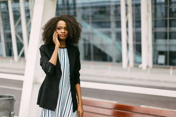 Close-up retrato horizontal da bela menina afro-americana séria falando através do telefone móvel . — Fotografia de Stock