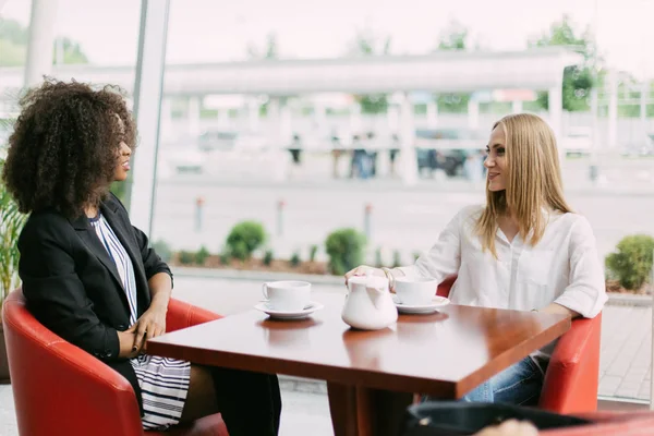 Vrolijke vergadering van twee vrienden in het café. Een van hen is Afro-Amerikaanse. — Stockfoto