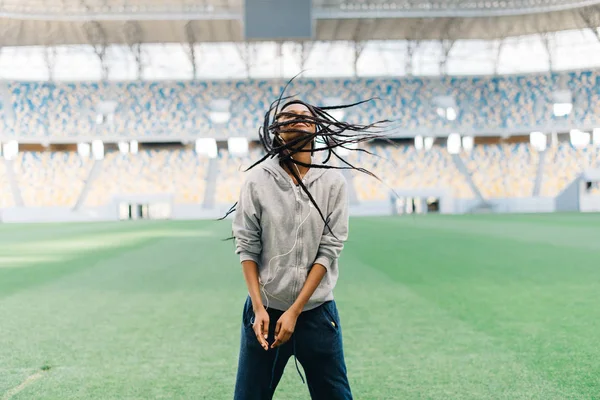 El enérgico retrato de medio cuerpo del alegre adolescente afroamericano agitando el pelo en el estadio . — Foto de Stock