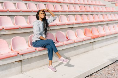 Uzaktan pembe koltuklar stadyum üzerinde otururken arıyorsunuz kulaklık atletik Afro-Amerikan genç yatay görünüm.