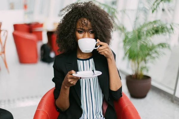 De charmante Afro-Amerikaanse vrouw is genieten van het kopje koffie in het café. — Stockfoto