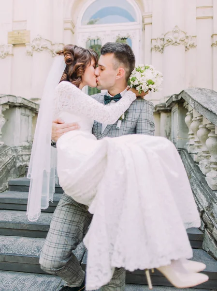 O retrato de close-up do noivo beijando a noiva enquanto carrega . — Fotografia de Stock