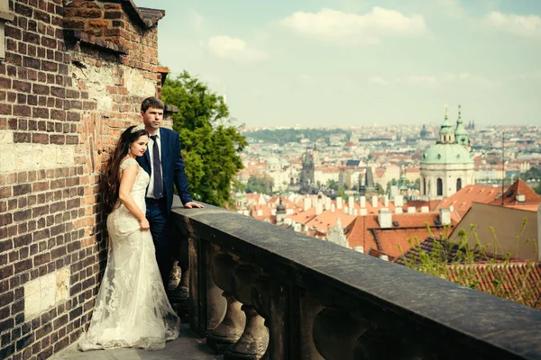 Yeni evli çift eski meadieval Balkonda duran ve Prag Panoraması zevk şık giyinmiş.