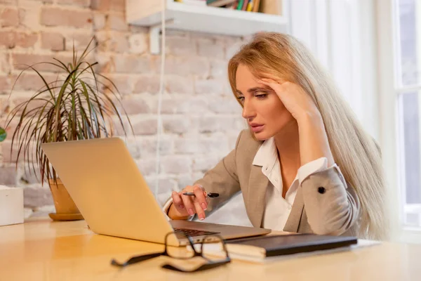 Rubia de pelo largo trabajando con su portátil en una bonita oficina. Mujer con ropa de bussunes . —  Fotos de Stock