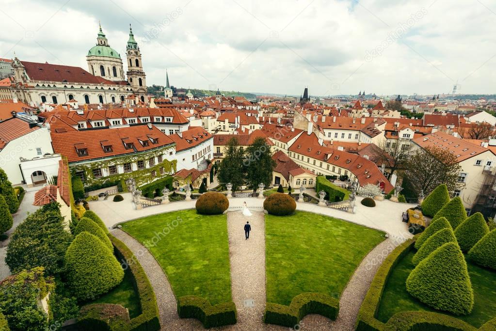 The panorama view of Prague. The down view of the walking newlywed couple along the park.