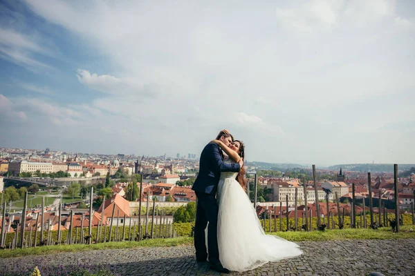Belo retrato ourdoor do casal recém-casado alegre abraçando no fundo da cidade antiga - Praga . — Fotografia de Stock