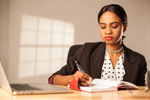 Empresaria sentada en su lugar de trabajo y escribiendo algo en su cuaderno . —  Fotos de Stock