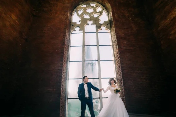 Casal recém-casado posando na frente da velha catedral gótica janela arqueada com tracery — Fotografia de Stock