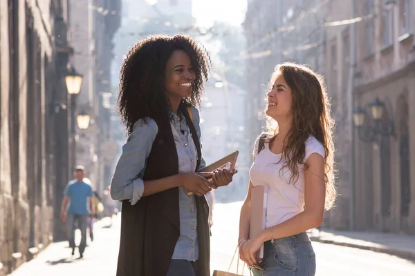 Duas raparigas felizes na rua e a conversar umas com as outras. Uma rapariga é afro-americana. . — Fotografia de Stock