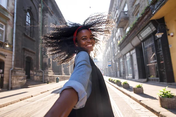 Foto de menina negra feliz andando na rua. Sorriso brilhante e cabelo encaracolado . — Fotografia de Stock