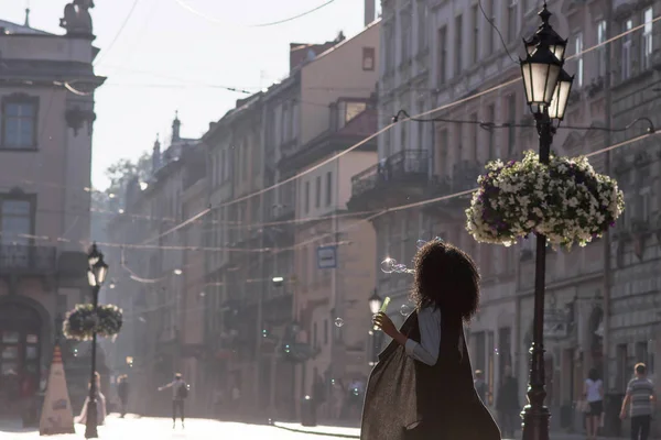 Крупним планом чорношкіра дівчина п'є вино на вулиці. Дівчина в костюмі. Чудовий вид на місто на фоні . — стокове фото