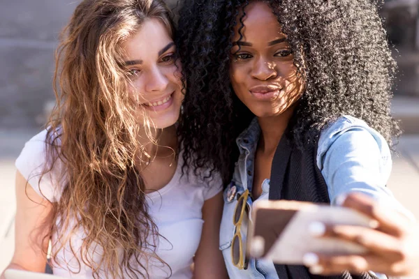 Close up tiro de duas meninas bonitas fazendo selfie. Uma menina é preta com cabelo encaracolado escuro . — Fotografia de Stock