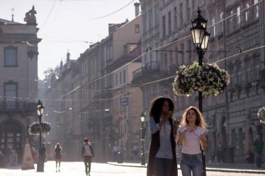 Şehir merkezinde yürüyüş kabarcık üfleyiciler iki güzel kızla. Bir kız güzel kıvırcık saçlı siyah.