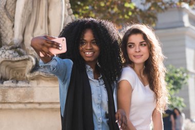 Anıtın selfie yapma iki güzel kızın görüntüsünü kapatın. Bir kız uzun siyah kıvırcık saçlı siyah.