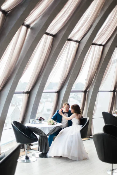 Full-length vertical photo of the newlyweds sitting in the moder nrestaurant. — Stock Photo, Image