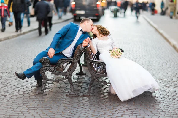 Close-up view of the kissing newlyweds while sitting on the bench. — Stock Photo, Image