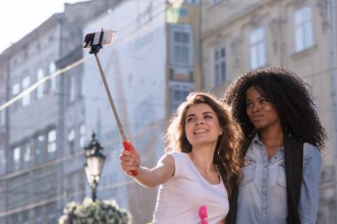 İki güzel kız selfie yapma gülümsedi. Kızlar güzel mimari ile sokakta daimi.