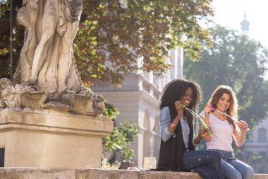 Kabarcık üfleyiciler ellerinde ile şehir merkezinde oturan gülümsüyor arkadaşlar. Güneşli gün ve rahat yaşam tarzı.