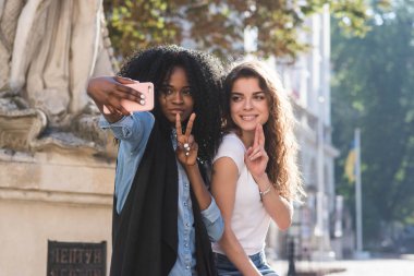 İki arkadaş selfie yapma. Anıtın oturan iki güzel kız. Bir kız siyah.