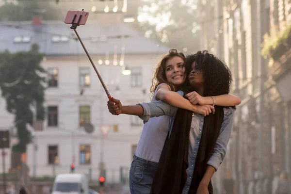 Dos amigos abrazándose y haciendo selfie en una hermosa calle. Día soleado . — Foto de Stock