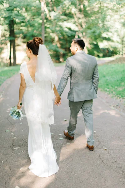 Noiva com costas nuas caminha com noivo no parque de verão — Fotografia de Stock