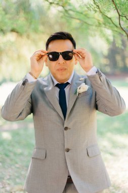 Gri takım elbiseli damat güneş gözlüğü ayarlar