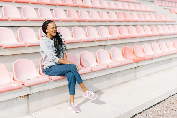 Visão horizontal do adolescente afro-americano rindo assistindo o jogo de esporte no estádio . — Fotografia de Stock