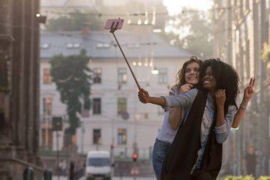 İki mutlu ve çekici kadın sokakta selfie yapma. Bir kadın siyah.
