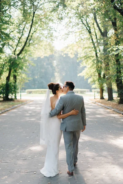 Regardez par derrière au couple de mariage embrasser dans le parc d'été — Photo