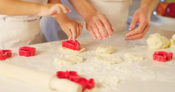 Datailní pohled rukou matka a její dítě, hnětení těsta a použití cookie formy. — Stock video