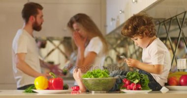 Hareket eden telefon içinde oynayan küçük sevimli çocuk arkasında mücadele duygusal uzaklaşmış anne arka plan. Annesi onun husdand tokat.