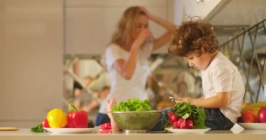 Ailesi arka plan kavga ederken cep telefonu onun kollarında küçük çocukla mutfağa oturuyor.