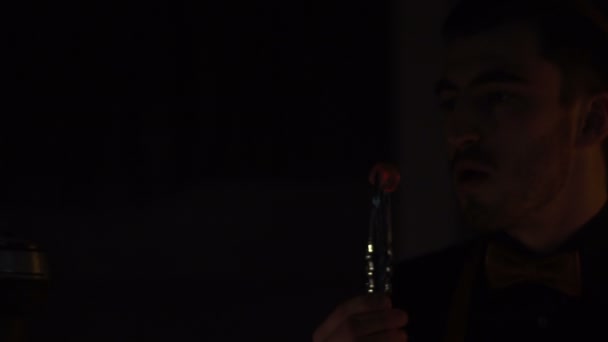 L'homme souffle sur le morceau de charbon dans la pièce sombre. Les étincelles tombent partout .