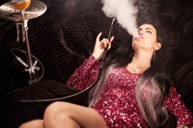 Seksi esmer yalan ve nargile büyük bir nargile duman exhaling.