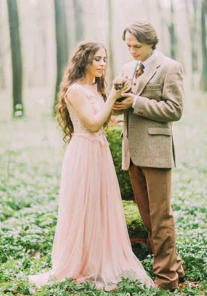 Fullängds fotot av årgång klädd brudgummen holding och bruden med långt lockigt hår är holding och petting brun vesslan. — Stockfoto